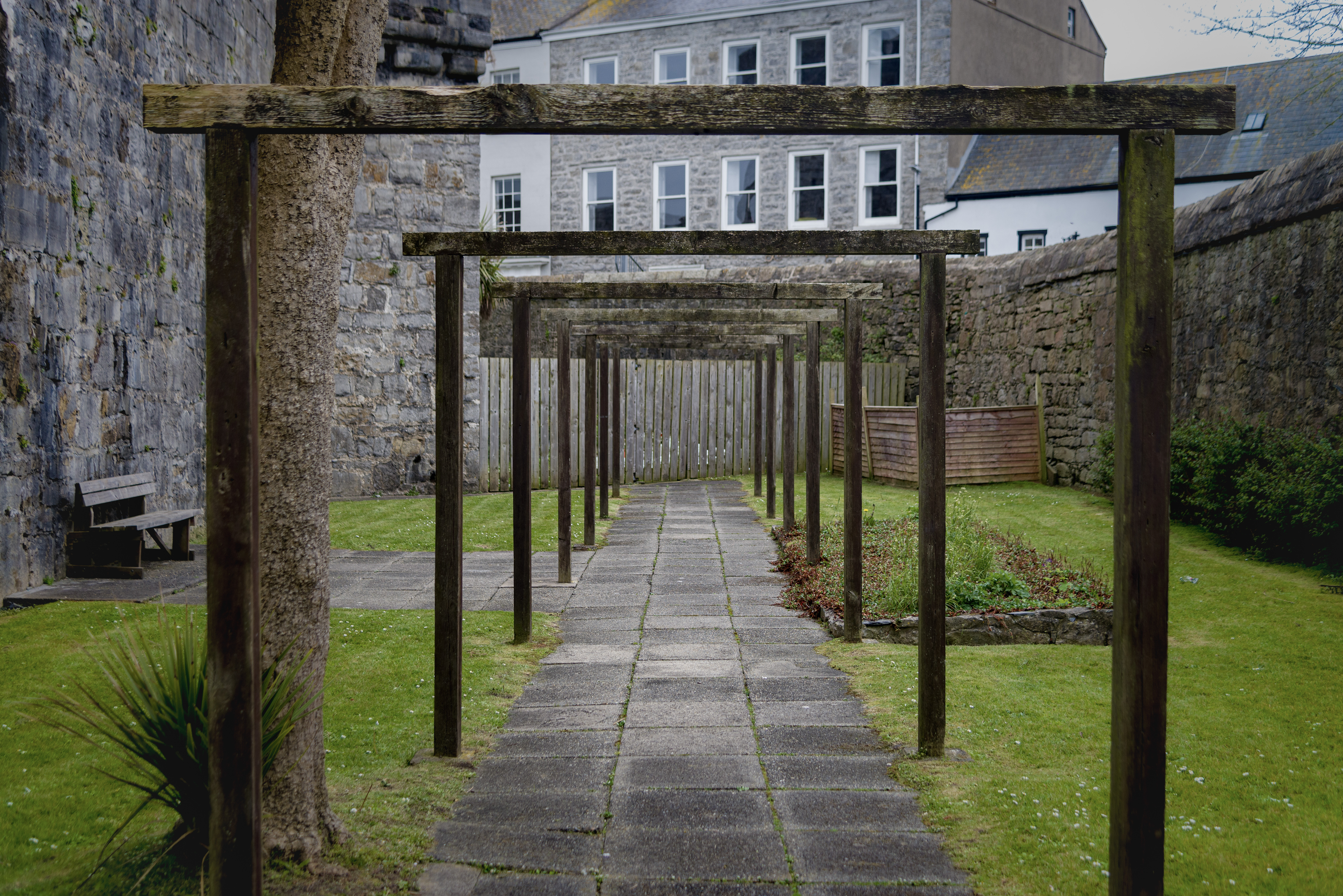 A series of square wooden arches stand in the garden of a castle, each one framing the one behind it.