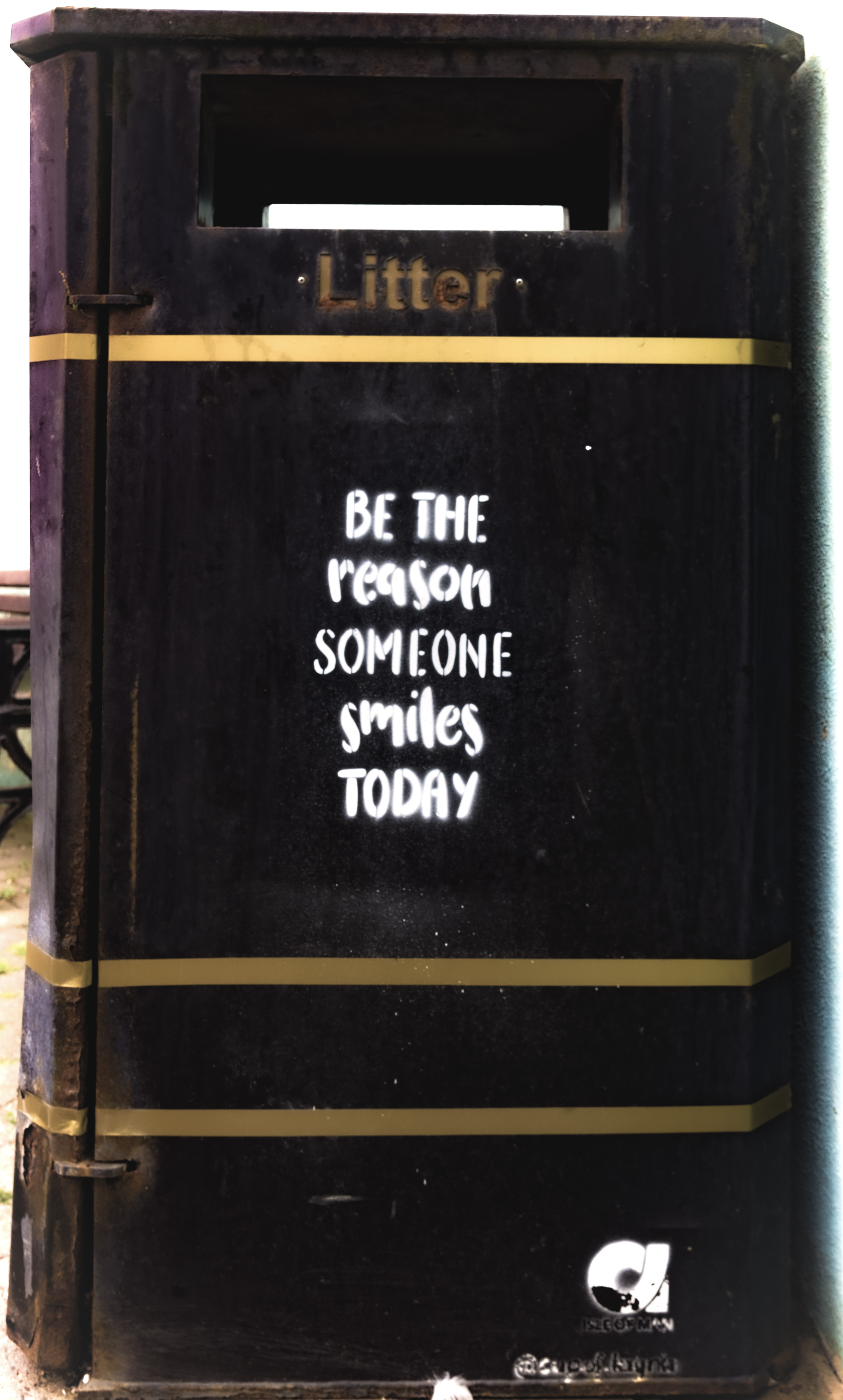 A black and gold litter bin with the words “Be the reason someone smiles today” spray painted on.