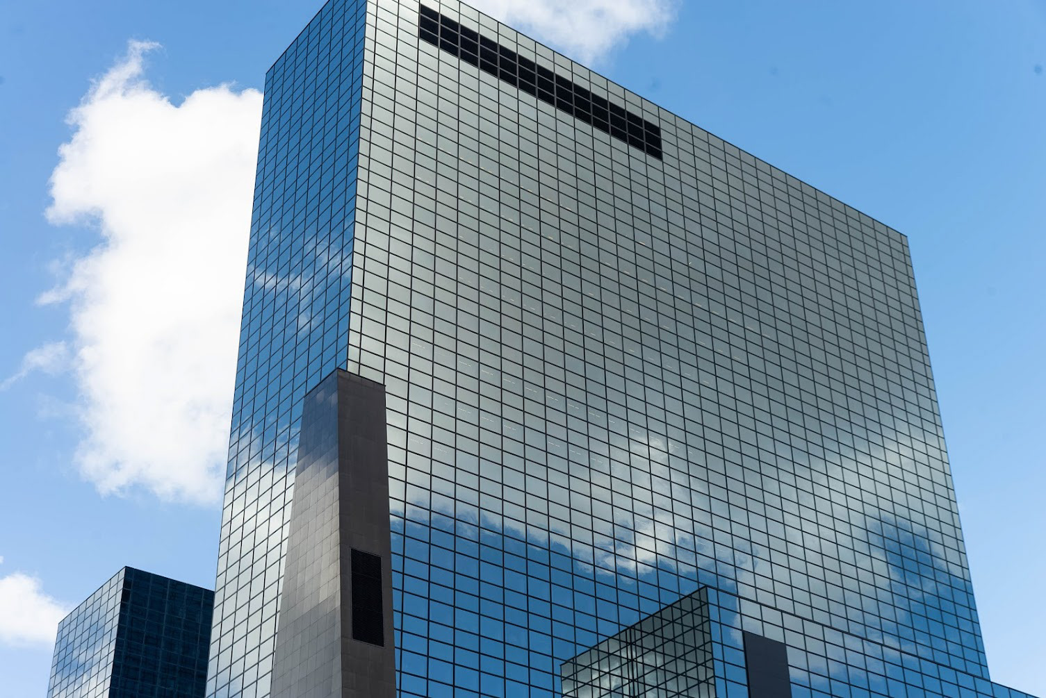 The Nationale Nederlanden building stands proud against the skyline, the blue of the sky reflected honestly in it’s glass facade, Rotterdam, NL