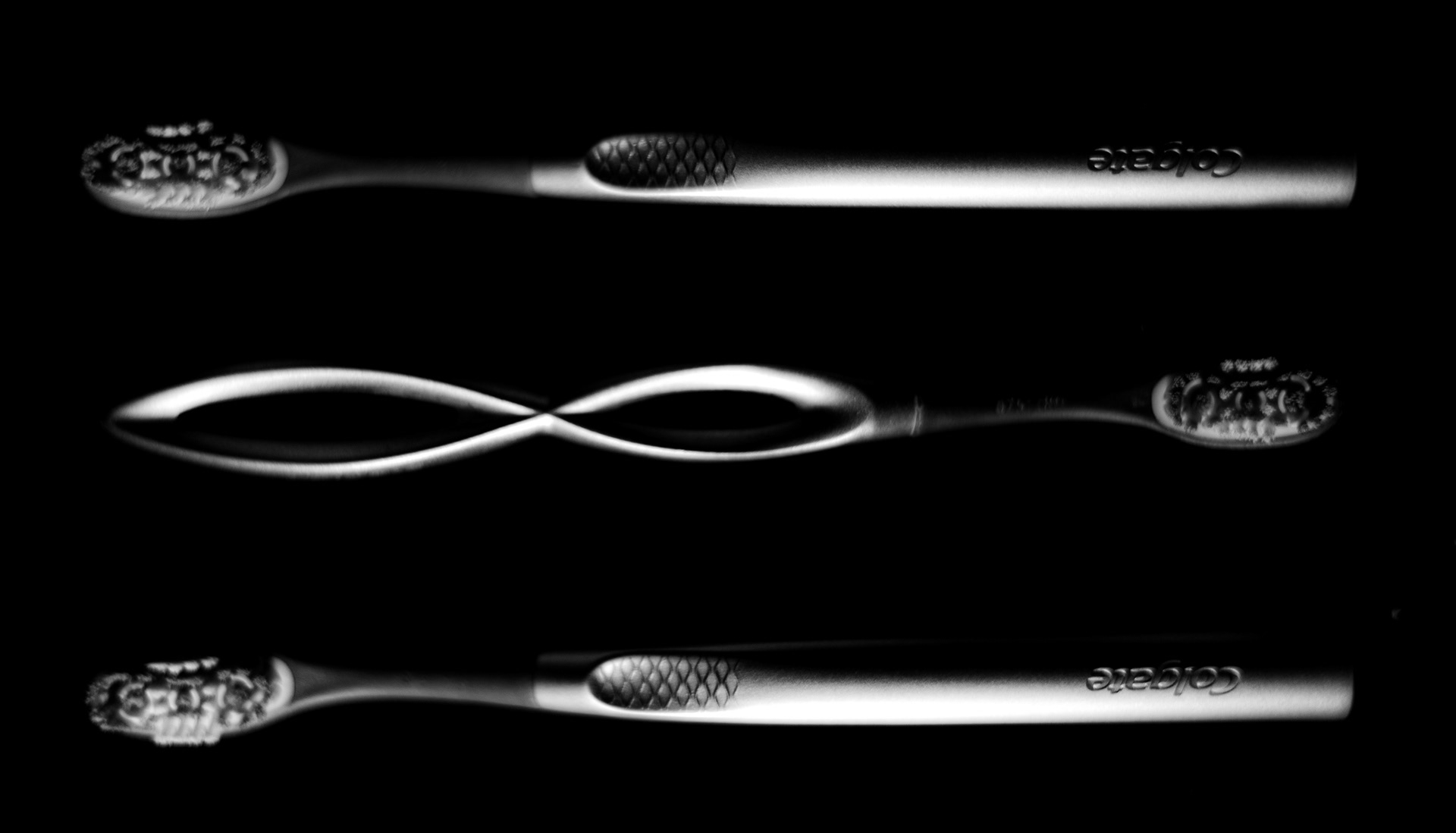 A black and white image of metal toothbrushes in an alternating pattern.