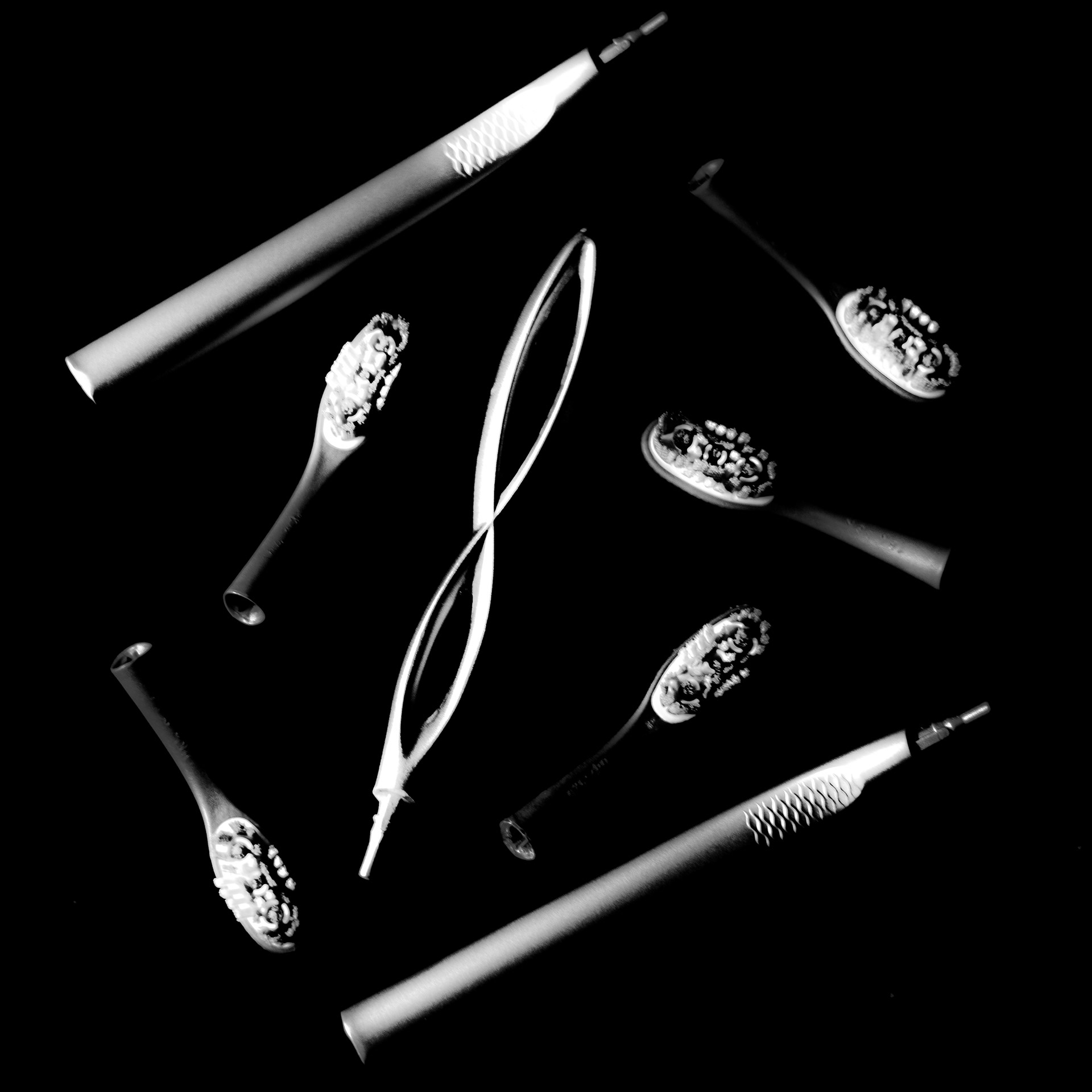 A medley of toothbrush heads and handles in black and white, arranged in a diamond shape.