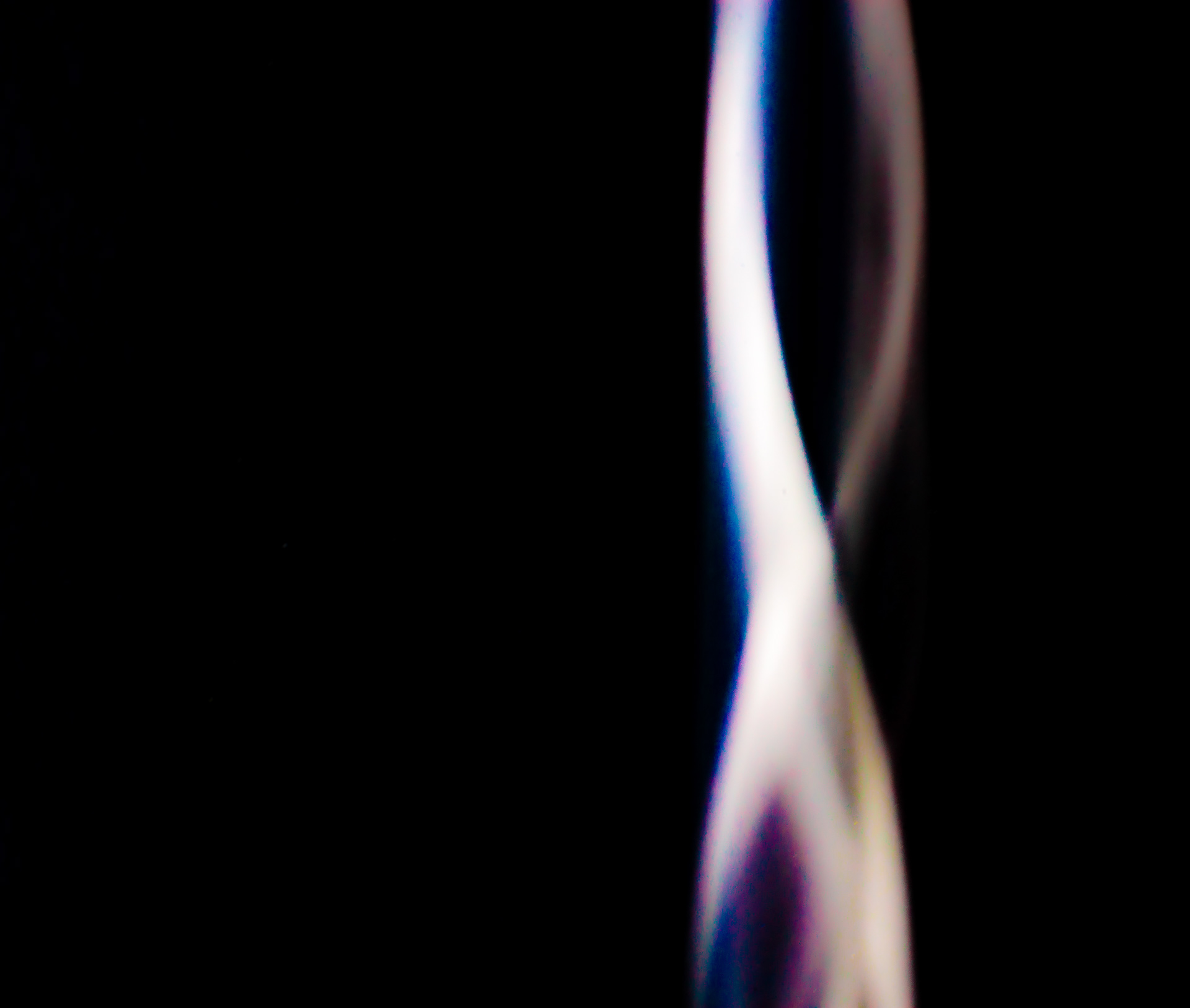 A blurry photo of a metal toothnrush handle creates a futuristc streak of light in a helical manner.